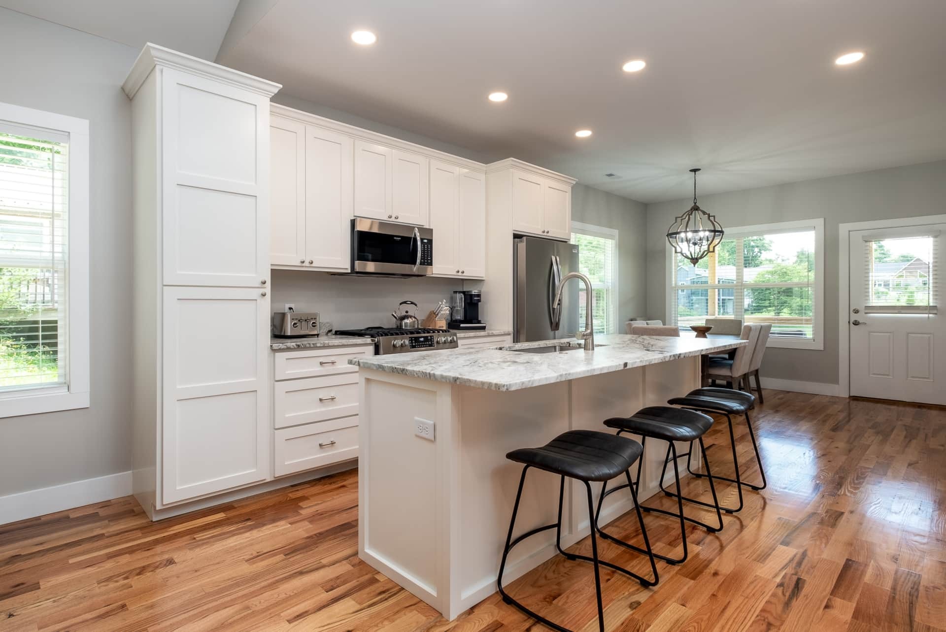 Kitchen with white cabinets, marble island, and leather barstools
