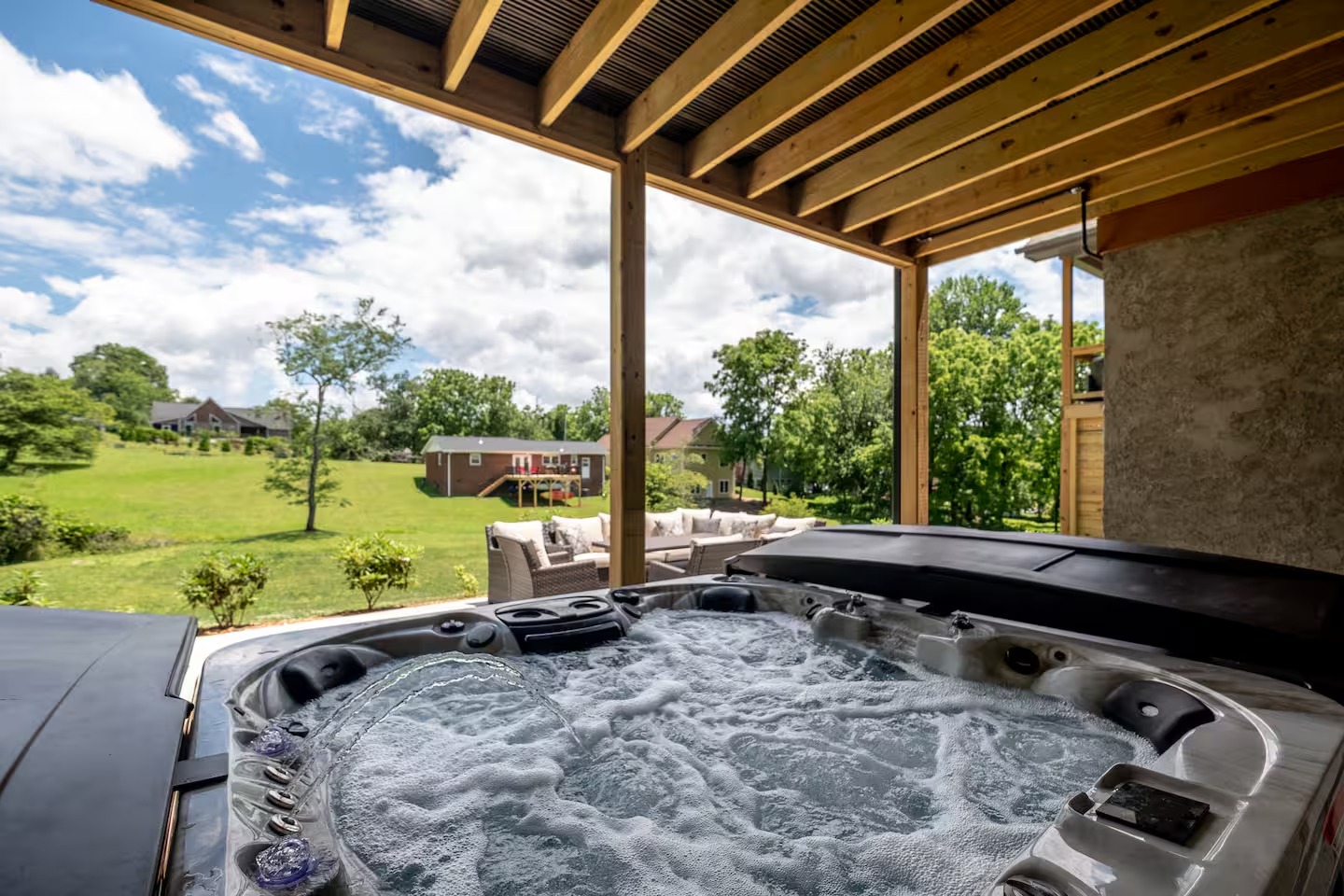 Hot tub on covered deck with view of green pasture