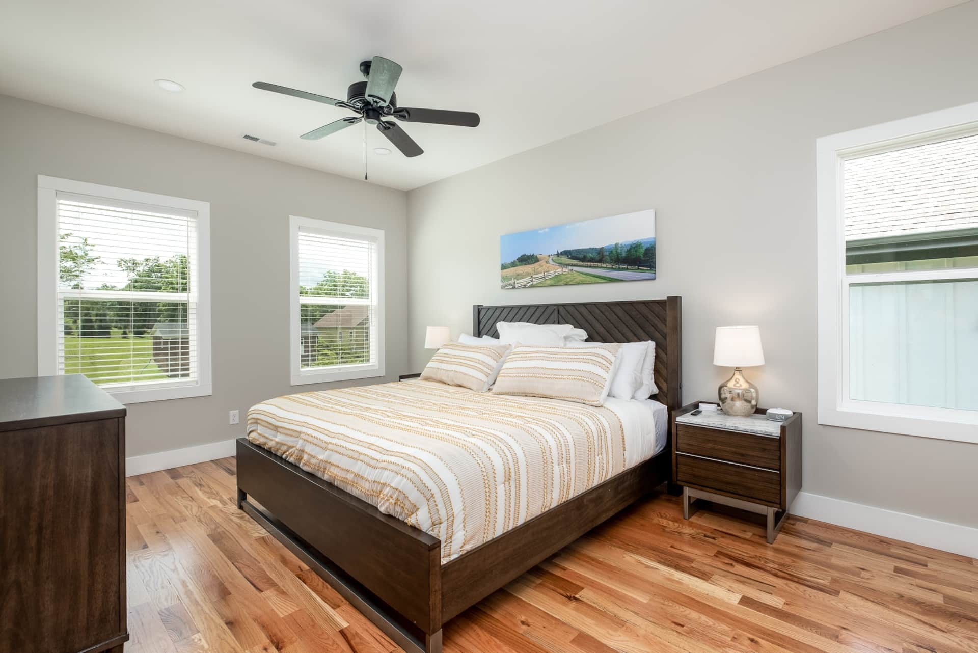 Bedroom with striped duvet and hardwood floors