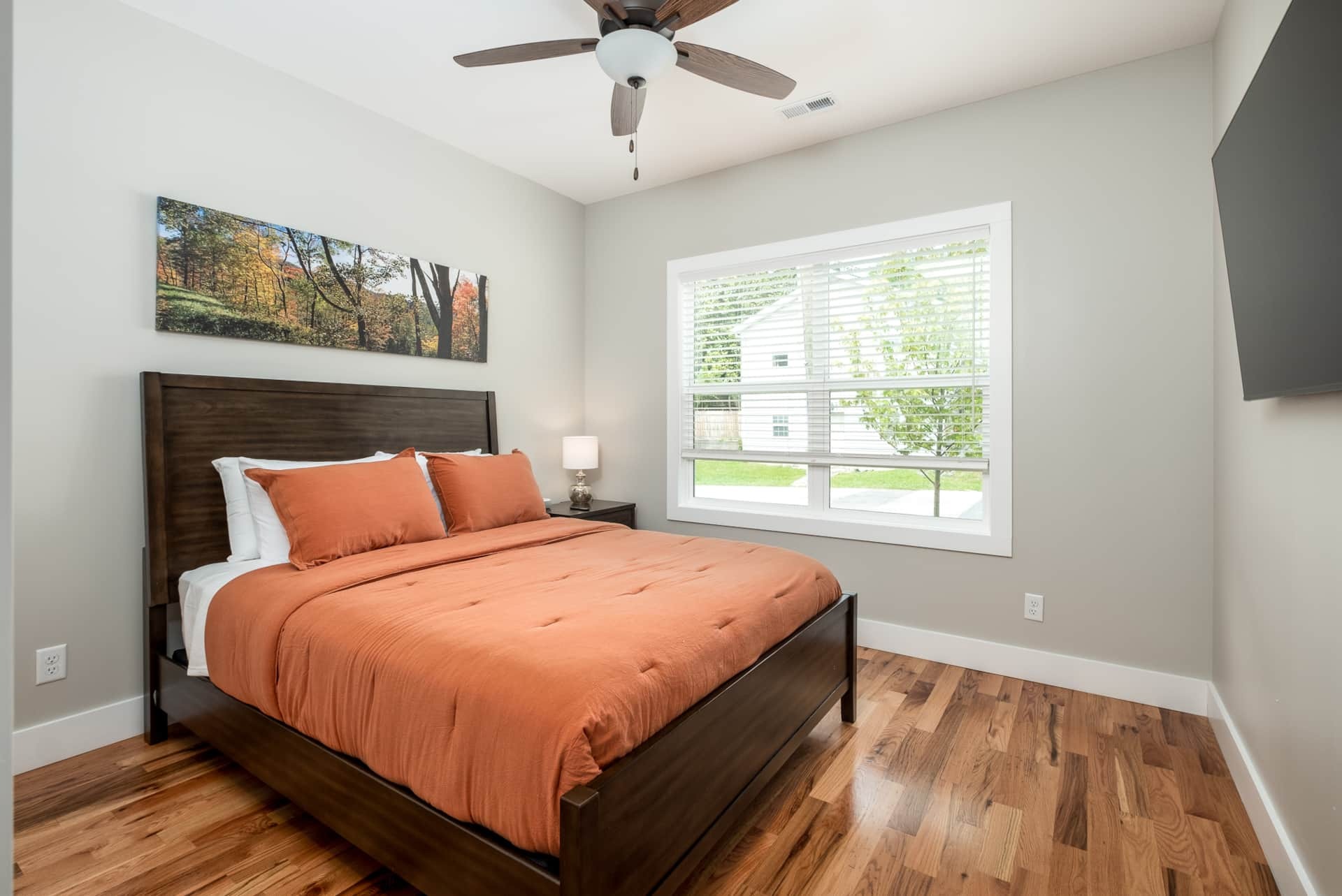 Bedroom with orange duvet and mountain canvas